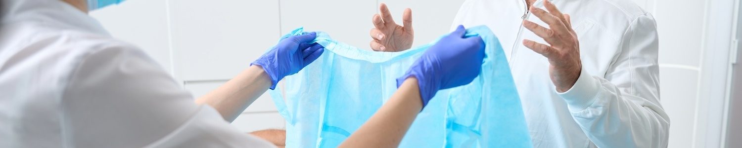 Surgeon puts on sterile clothes before the operation, he is assisted by a young nurse