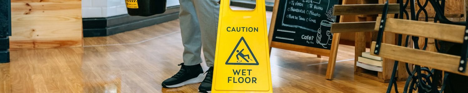 Worker placing wet floor sign after mopping the floor